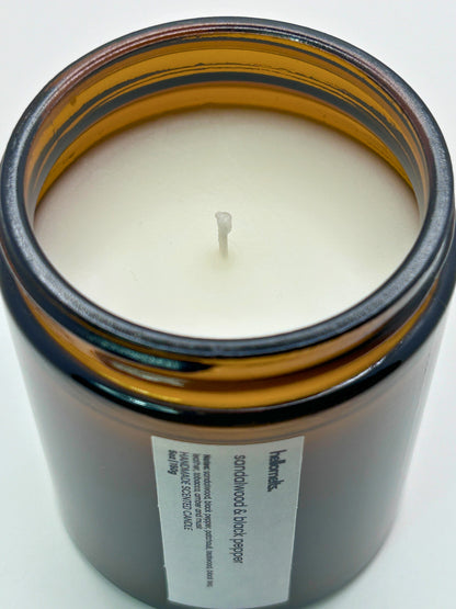 Close-up angled top-down view of Sandalwood & Black Pepper autumn scented candle by Hellomelts, showcasing the smooth wax in an amber jar from the Autumn Collection