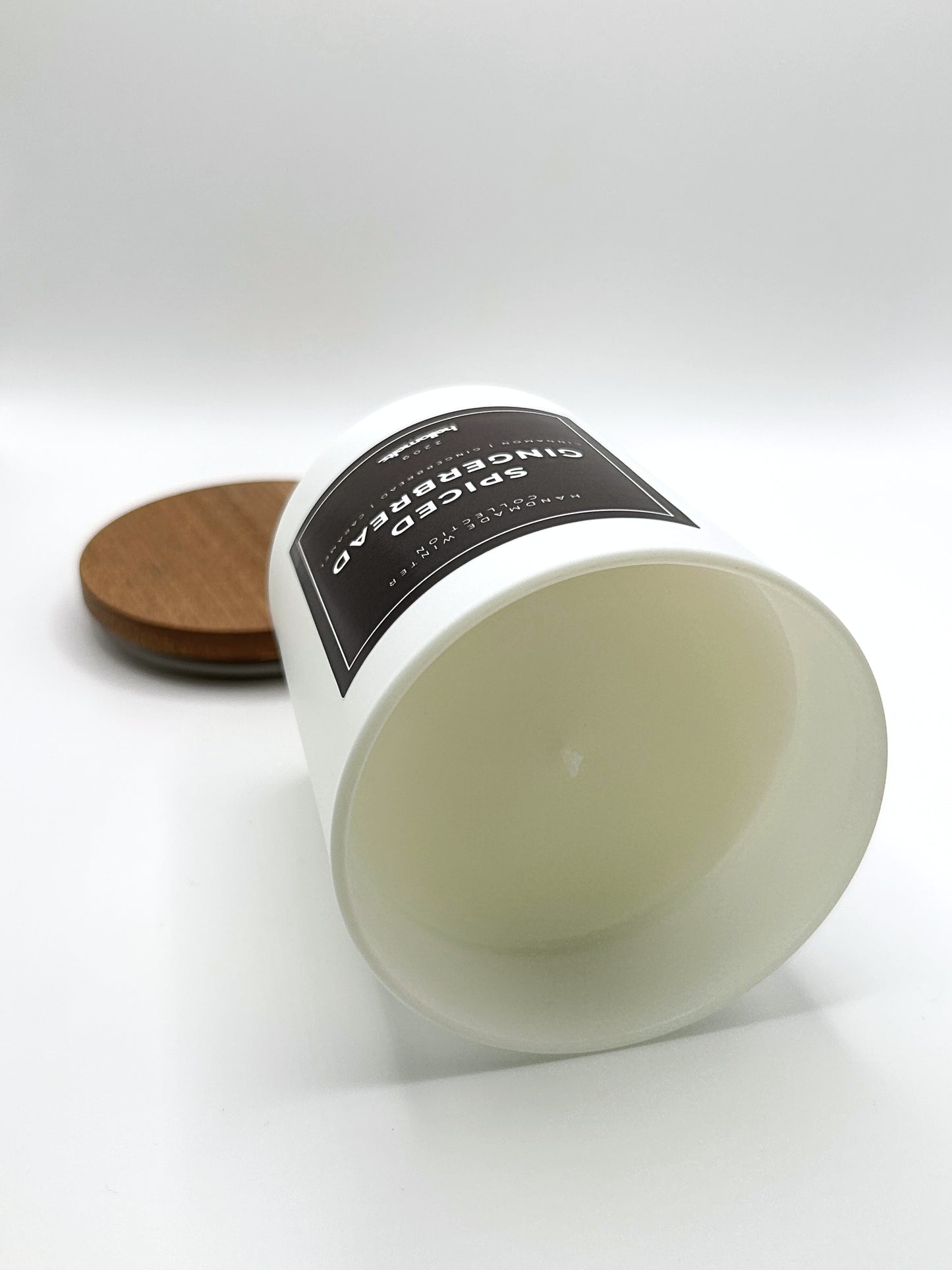 Spiced Gingerbread 220g candle laid on its side with the lid in the background, showing the matte white jar from the Hellomelts Winter Collection