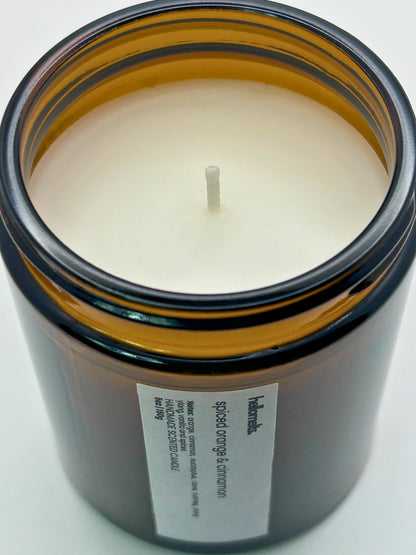 Close-up angled top-down view of Spiced Orange & Cinnamon autumn scented candle by Hellomelts, showcasing the smooth wax in an amber jar from the Autumn Collection