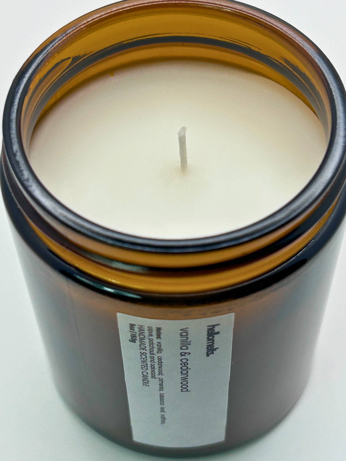 Close-up angled top-down view of Vanilla & Cedarwood autumn scented candle by Hellomelts, showcasing the smooth wax in an amber jar from the Autumn Collection