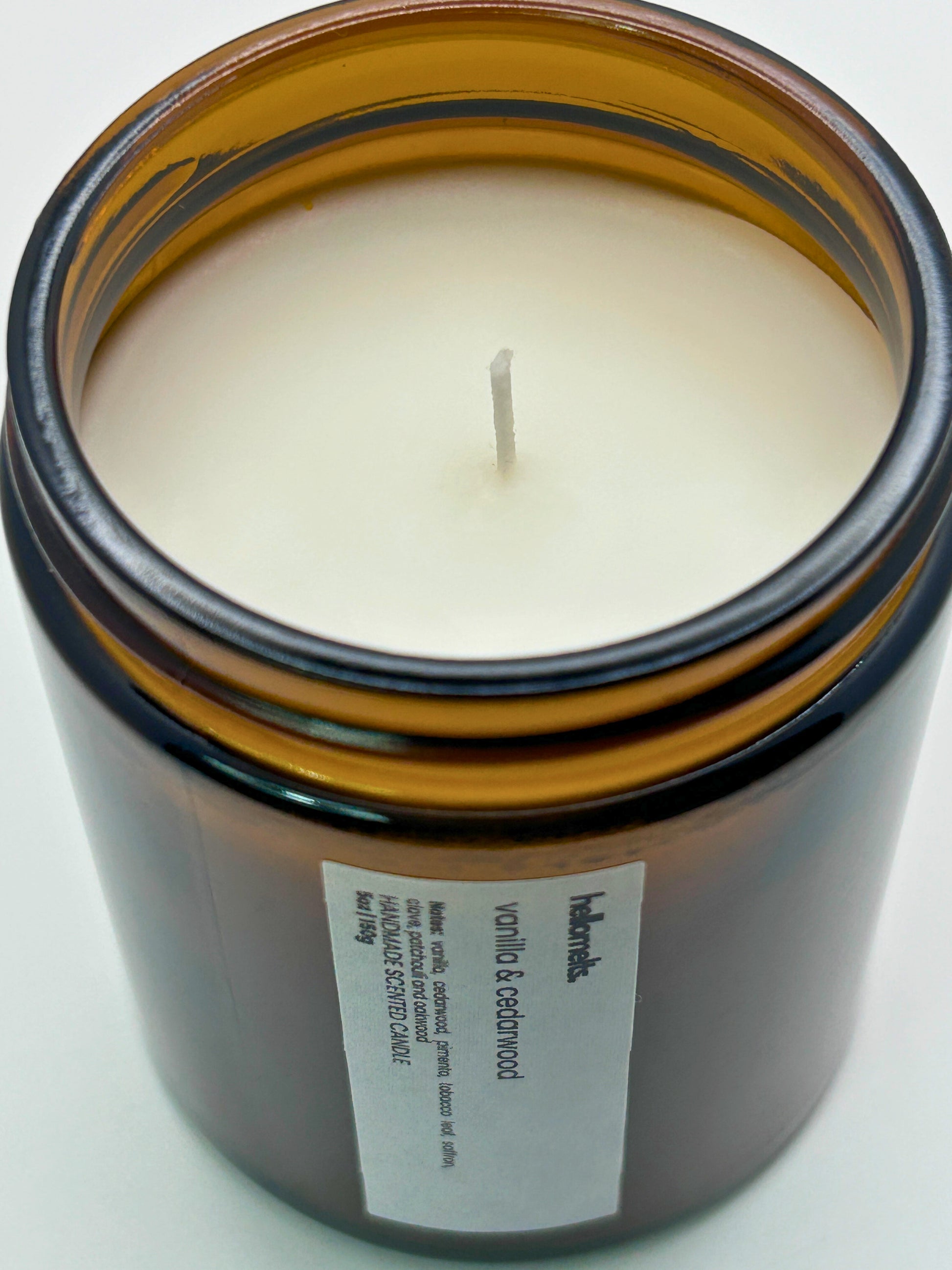 Close-up angled top-down view of Vanilla & Cedarwood autumn scented candle by Hellomelts, showcasing the smooth wax in an amber jar from the Autumn Collection