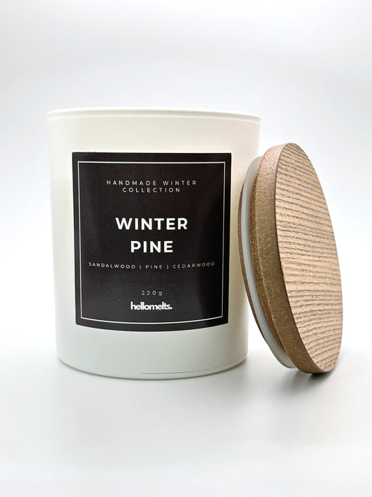 Winter Pine 220g candle angled-view image with the wooden lid leaning beside the jar, from the Hellomelts Winter Collection
