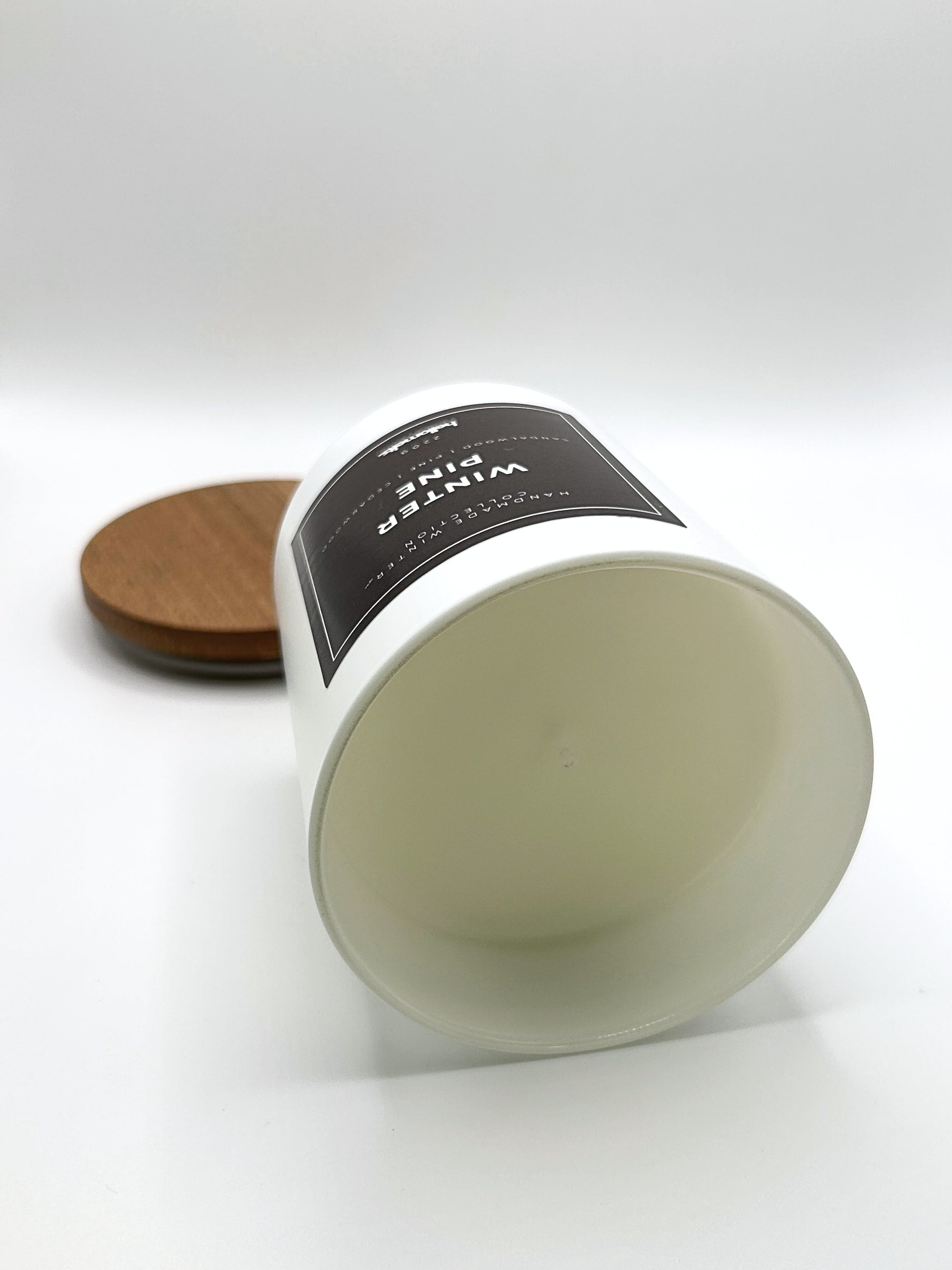 Winter Pine 220g candle laid on its side with the lid in the background, showing the matte white jar from the Hellomelts Winter Collection