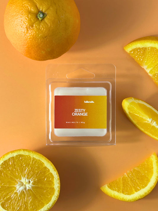 Zesty Orange wax melt bar in clear clamshell packaging, styled with fresh orange slices on a light background, Hellomelts Summer Collection