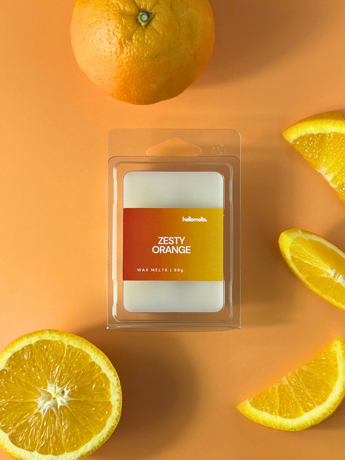Zesty Orange wax melt bar in clear clamshell packaging, styled with fresh orange slices on a light background, Hellomelts Summer Collection